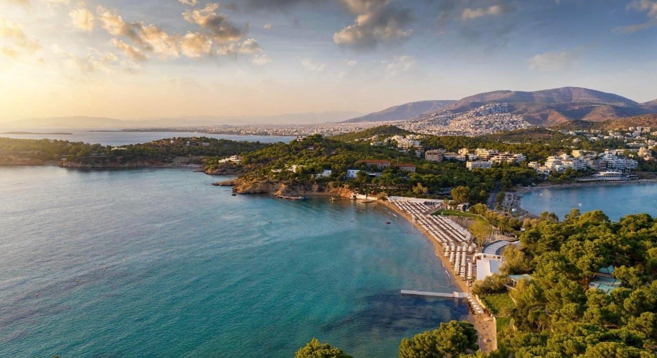Golden-hour aerial of Vouliagmeni Bay and its sheltered beach on the Athens Riviera