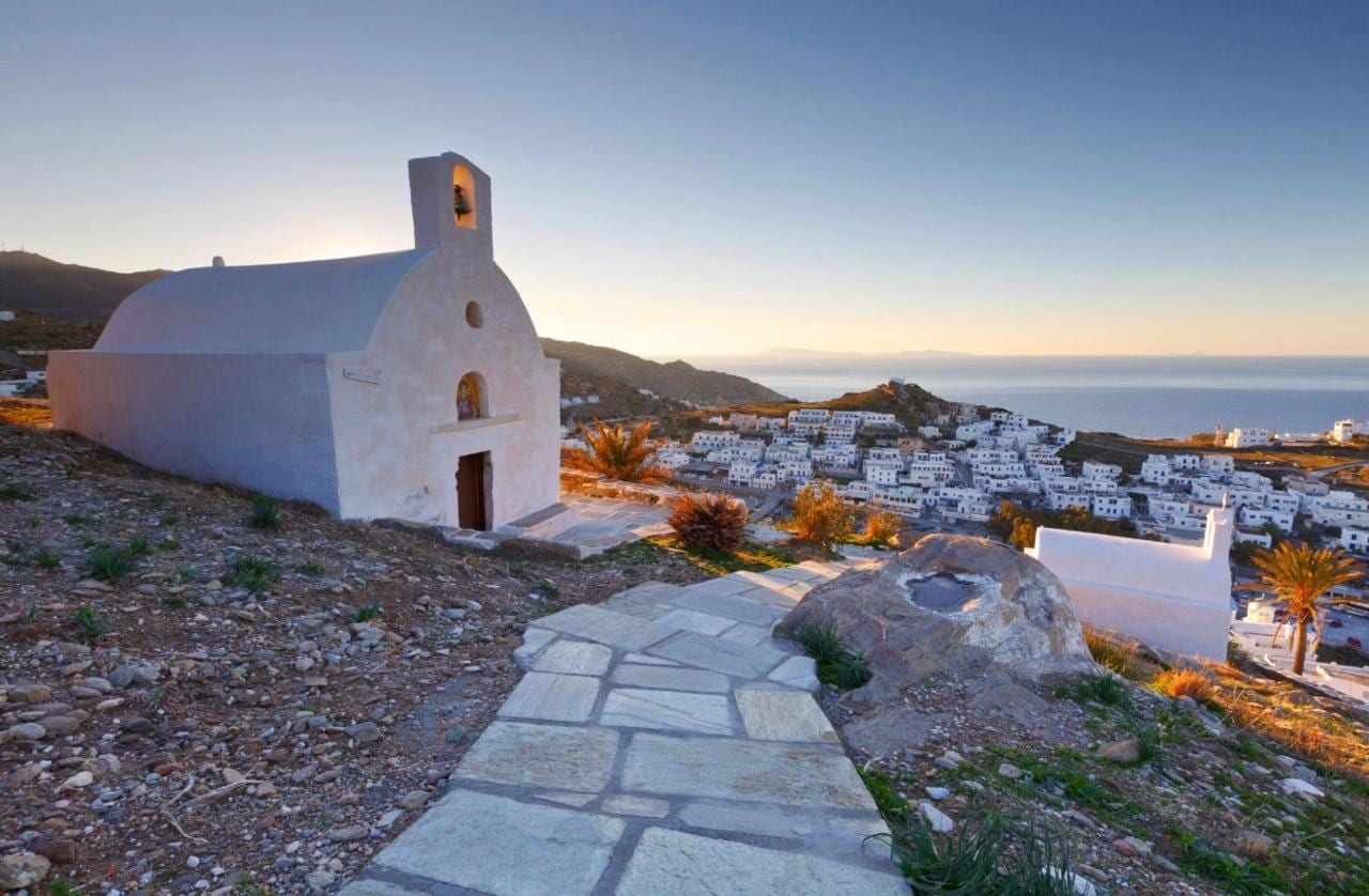 A hilltop chapel and stone path catching the last sun above Chora, Ios